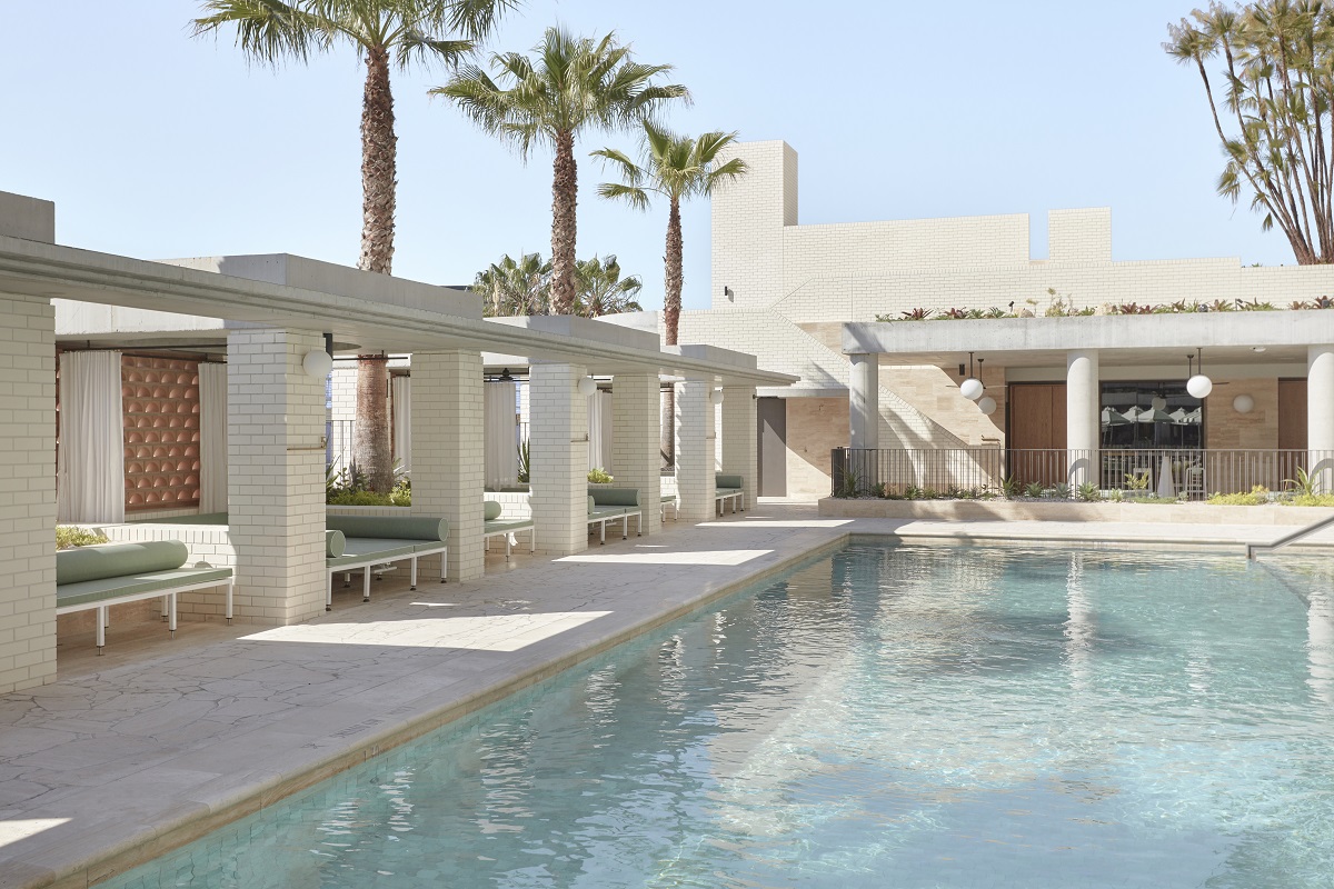 The Calile pool deck with green-cushioned cabanas and palms.